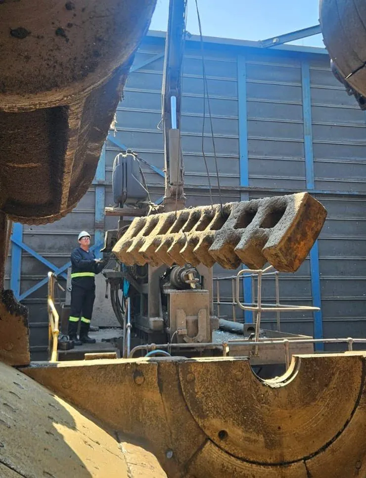 Técnico içando peça de desgaste durante manutenção de shredder